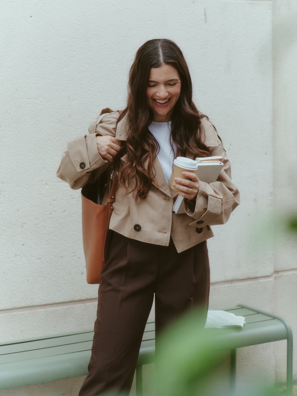 Guada laughing, holding a coffee and books
